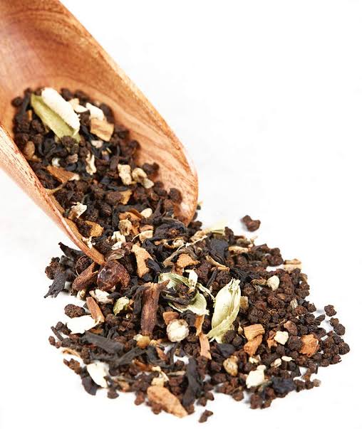 Spiced masala chai blend with cardamom, cinnamon and ginger in a wooden scoop